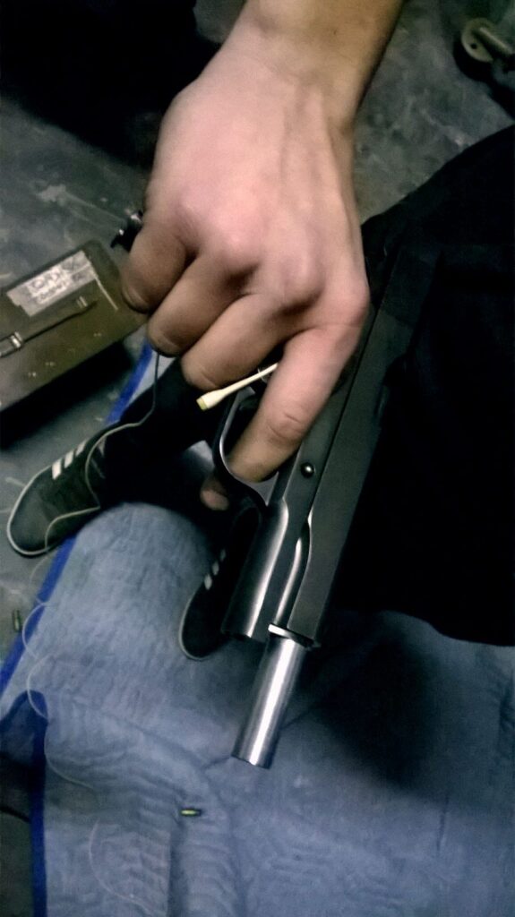 In a sound effects library reference image on Sonniss, a person holds a semi-automatic handgun barrel down, finger off trigger.