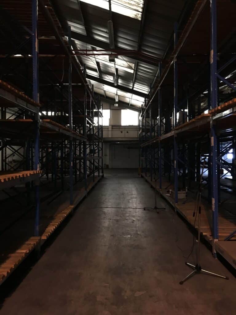 A sound effects library image: empty warehouse aisle for industrial ambience sfx, ideal for unique indoor warehouse reverbs.