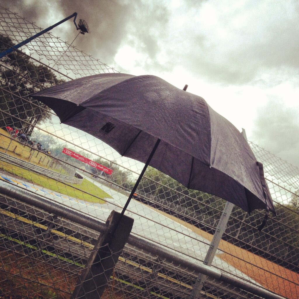 A black umbrella with raindrops by a metal fence—perfect ambient audio for a rainy racetrack SFX library on Sonniss.