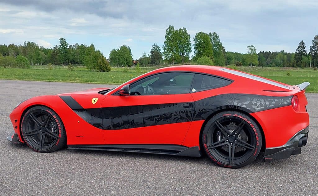 A red sports car with black detailing, parked on a paved surface, set against trees and a cloudy sky—perfect for your sfx library.
