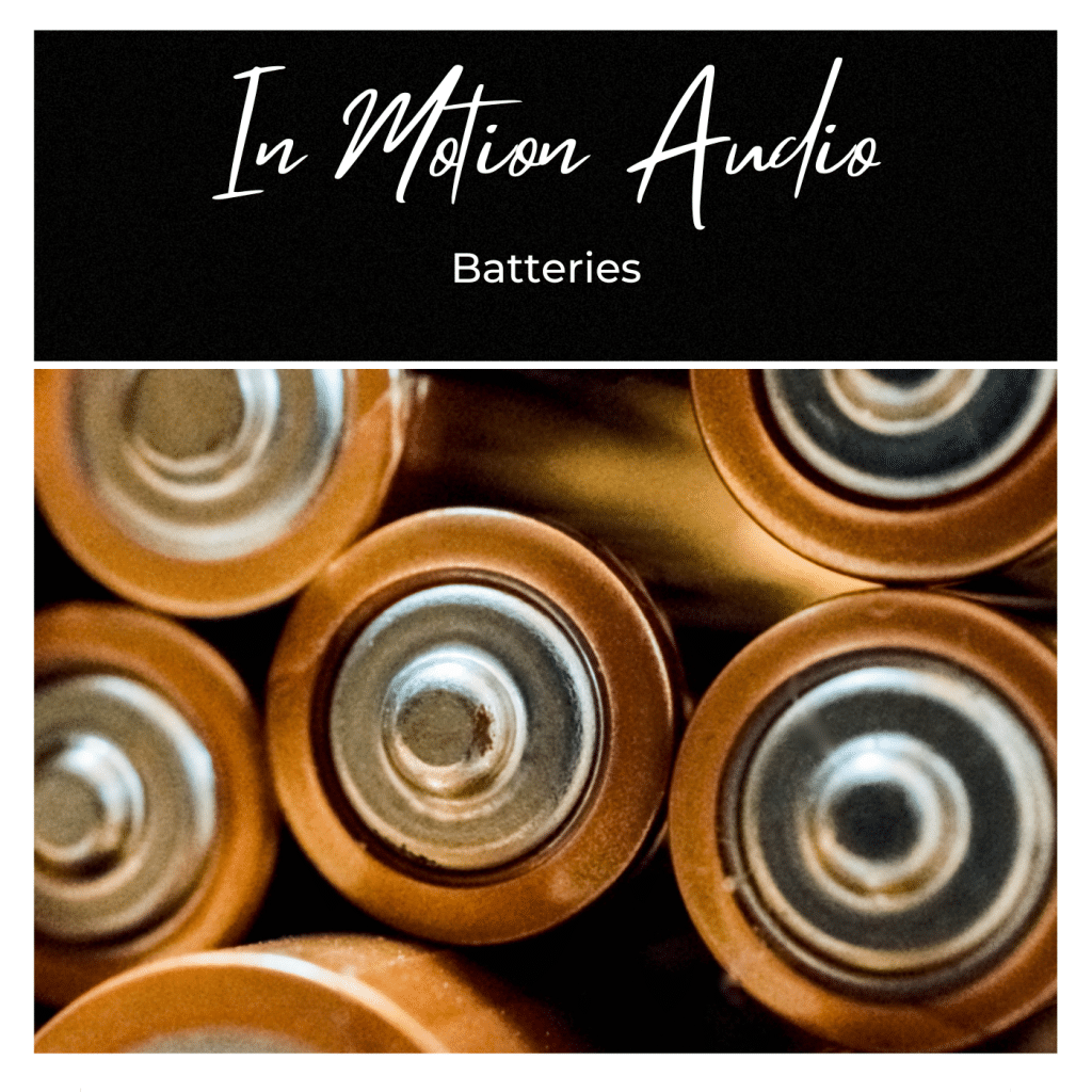 Several AA battery tops grouped closely together, with "In Motion Audio" and "Batteries" text above on a black background.