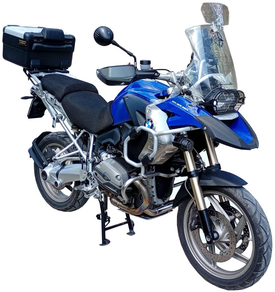 Blue and silver adventure motorcycle with windshield, side mirrors, black seat cover, and rear storage box on its center stand.