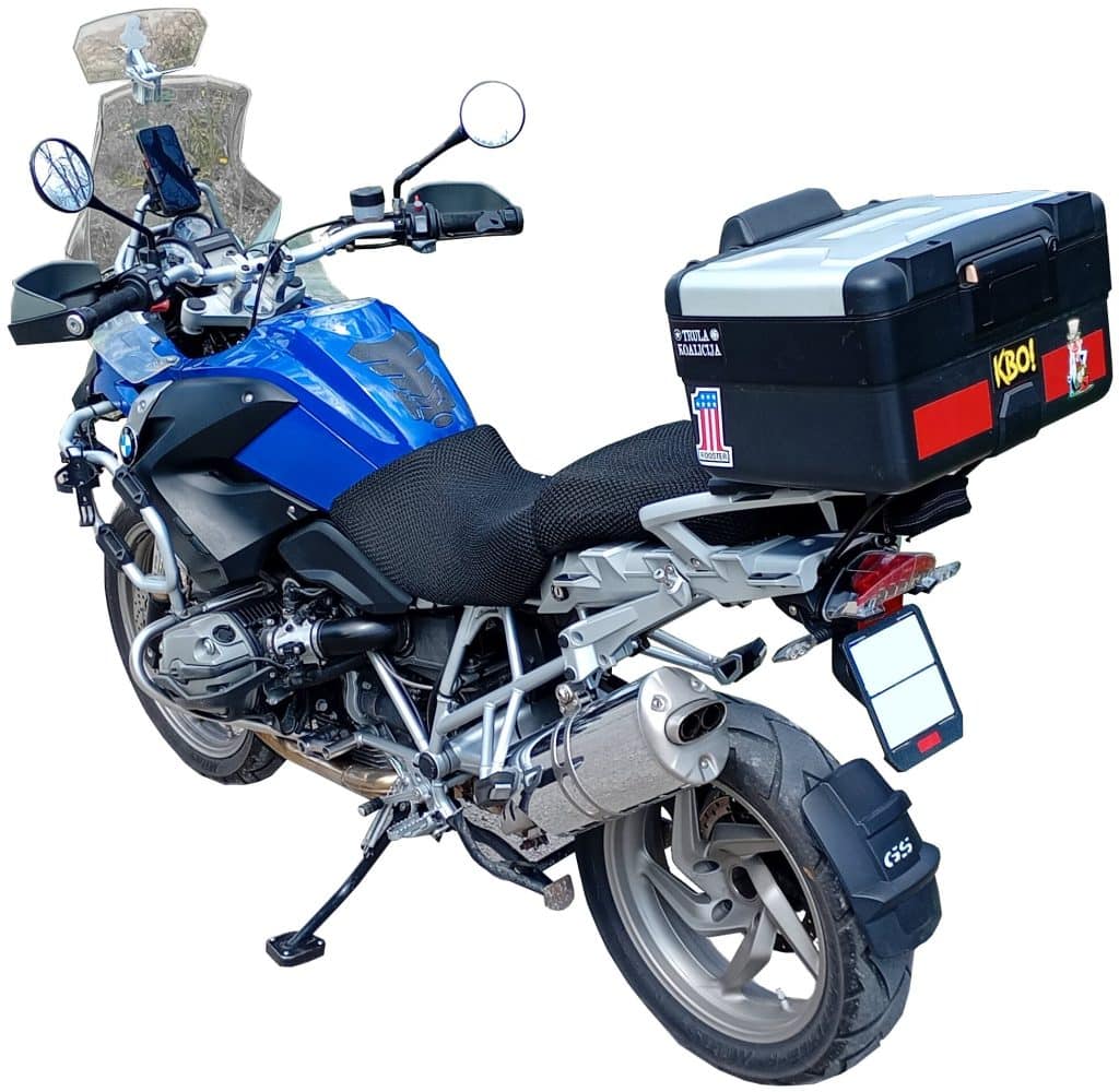 Blue touring motorcycle with windshield, side mirrors, and large black top case, parked on its stand, rear angled view.