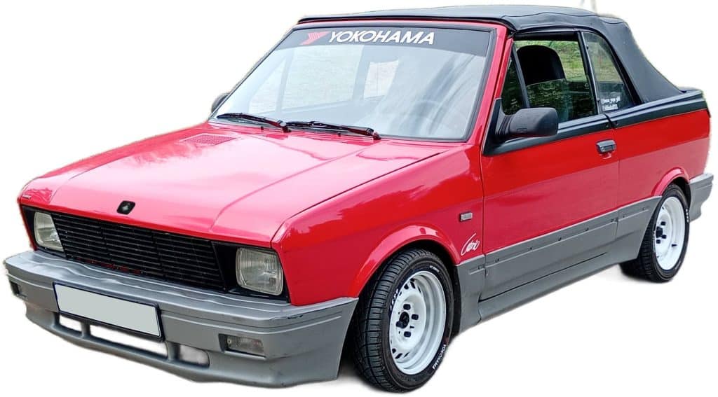 Red and gray convertible with black soft top, sporty wheels, and "Yokohama" on windshield, shown from front left angle.