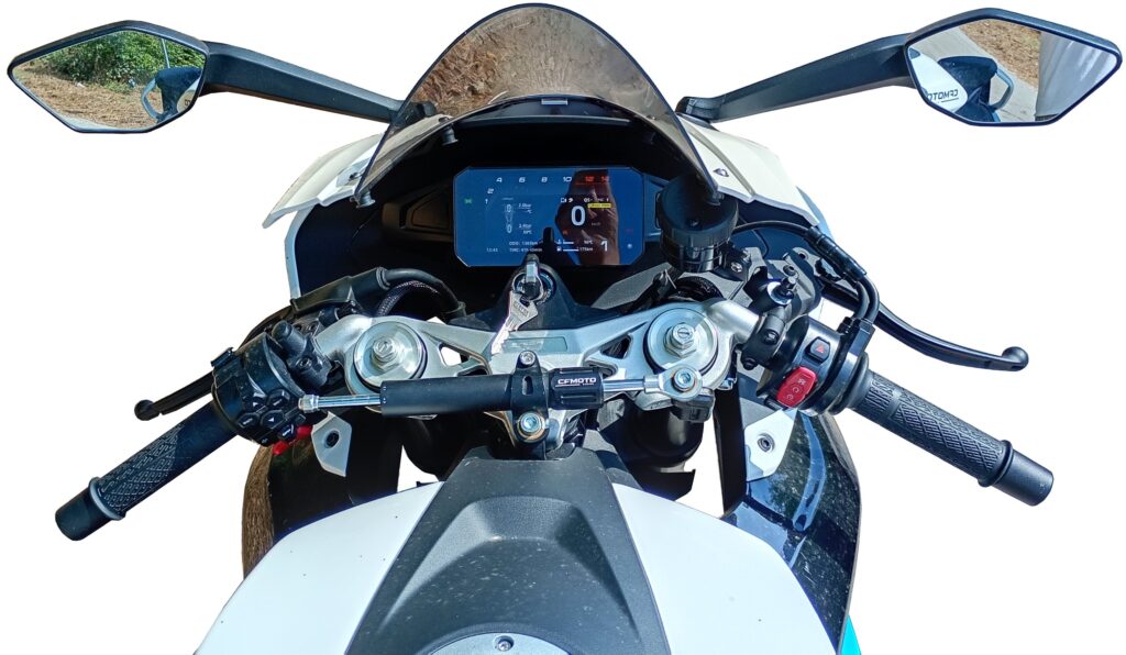 Motorcycle cockpit from the rider’s perspective, featuring handlebars, mirrors, a digital dashboard display, and various controls on a white and blue motorcycle.