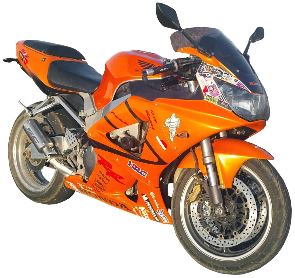 Orange 2000 Honda CBR929RR sport bike featuring a black seat, tinted windscreen, and various sponsor decals.