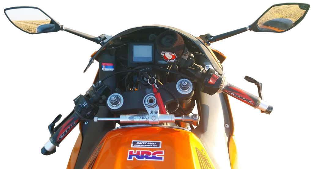 Handlebars, dashboard, and fuel tank visible from the rider’s seat of an orange 2000 Honda CBR929RR sport bike.