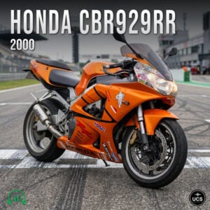 Orange 2000 Honda CBR929RR sport bike parked on a racetrack starting grid.