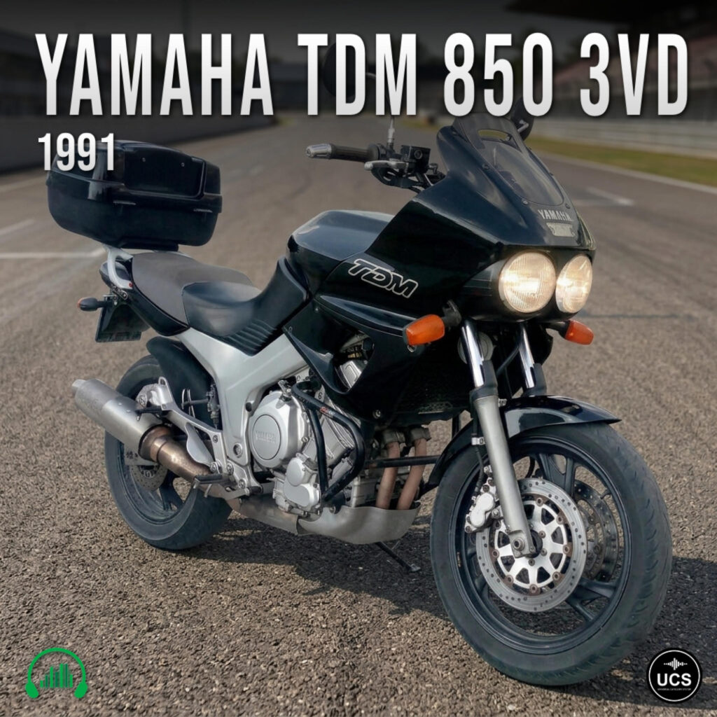 Black 1991 Yamaha TDM 850 3VD sport touring motorbike with twin headlamps and a rear top box on tarmac.